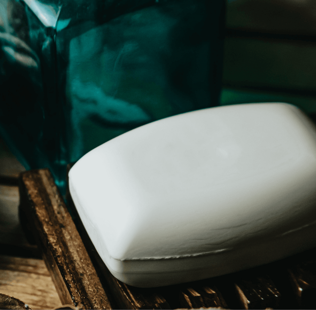 White soap bar on a wooden surface with a green cloth in the background